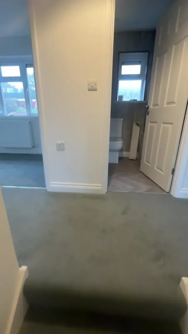 Carpeted upper landing with decorated walls and internal doors
